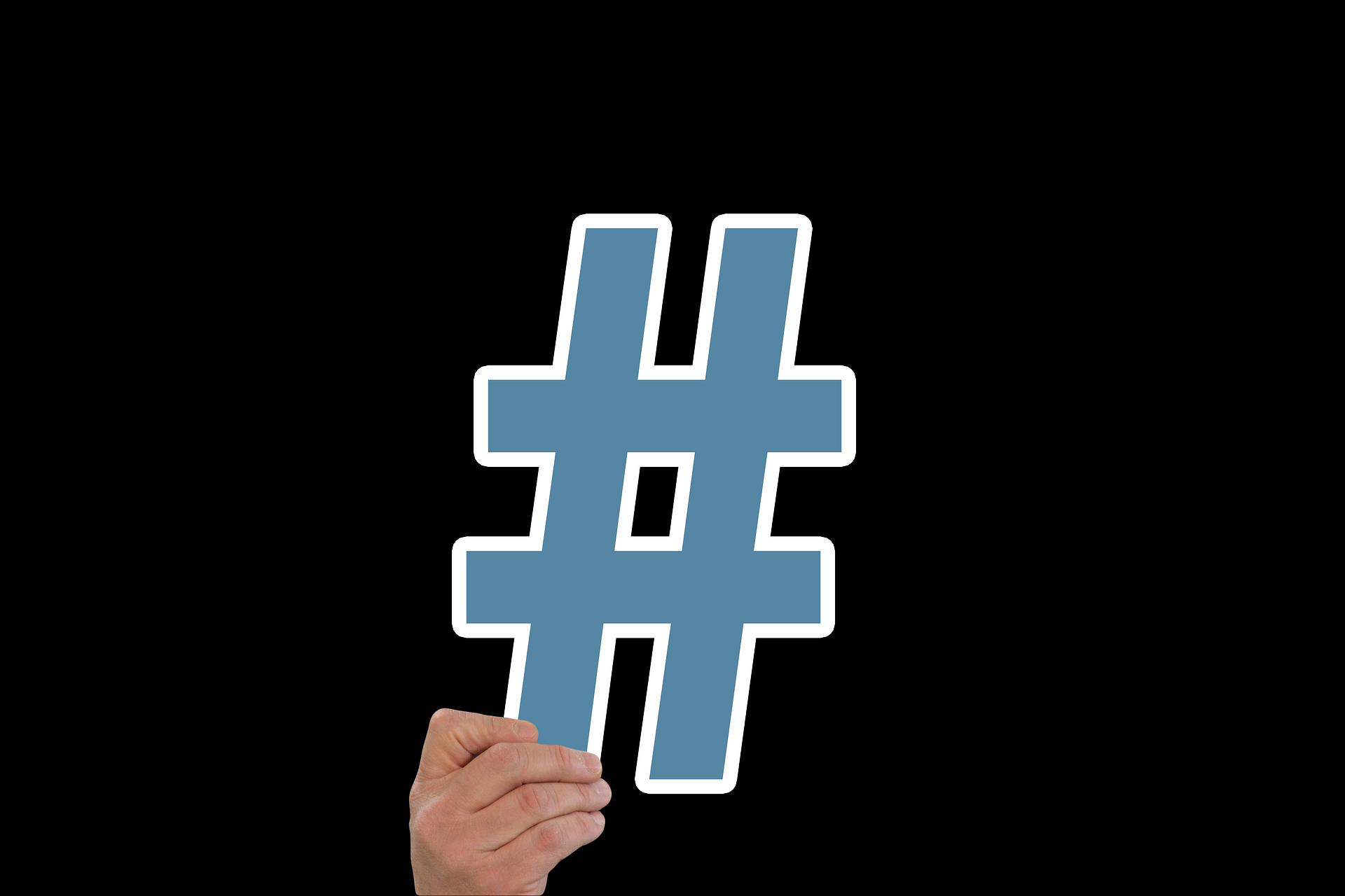 blue hashtag held in hand in black background