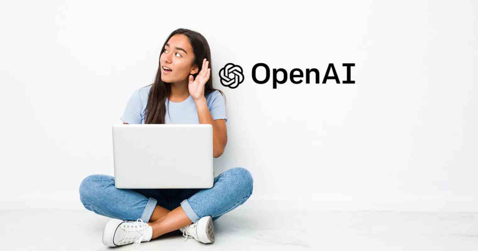 a girl holding laptop sitting down beside an openai logo